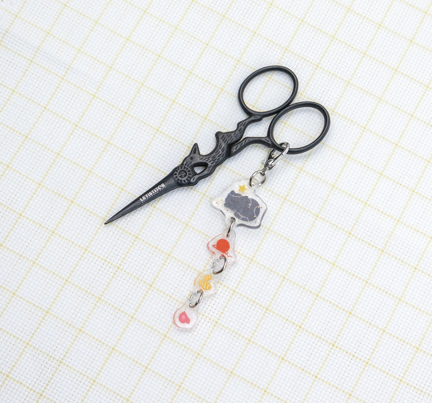 Decorative scissors with a keychain on a grid background