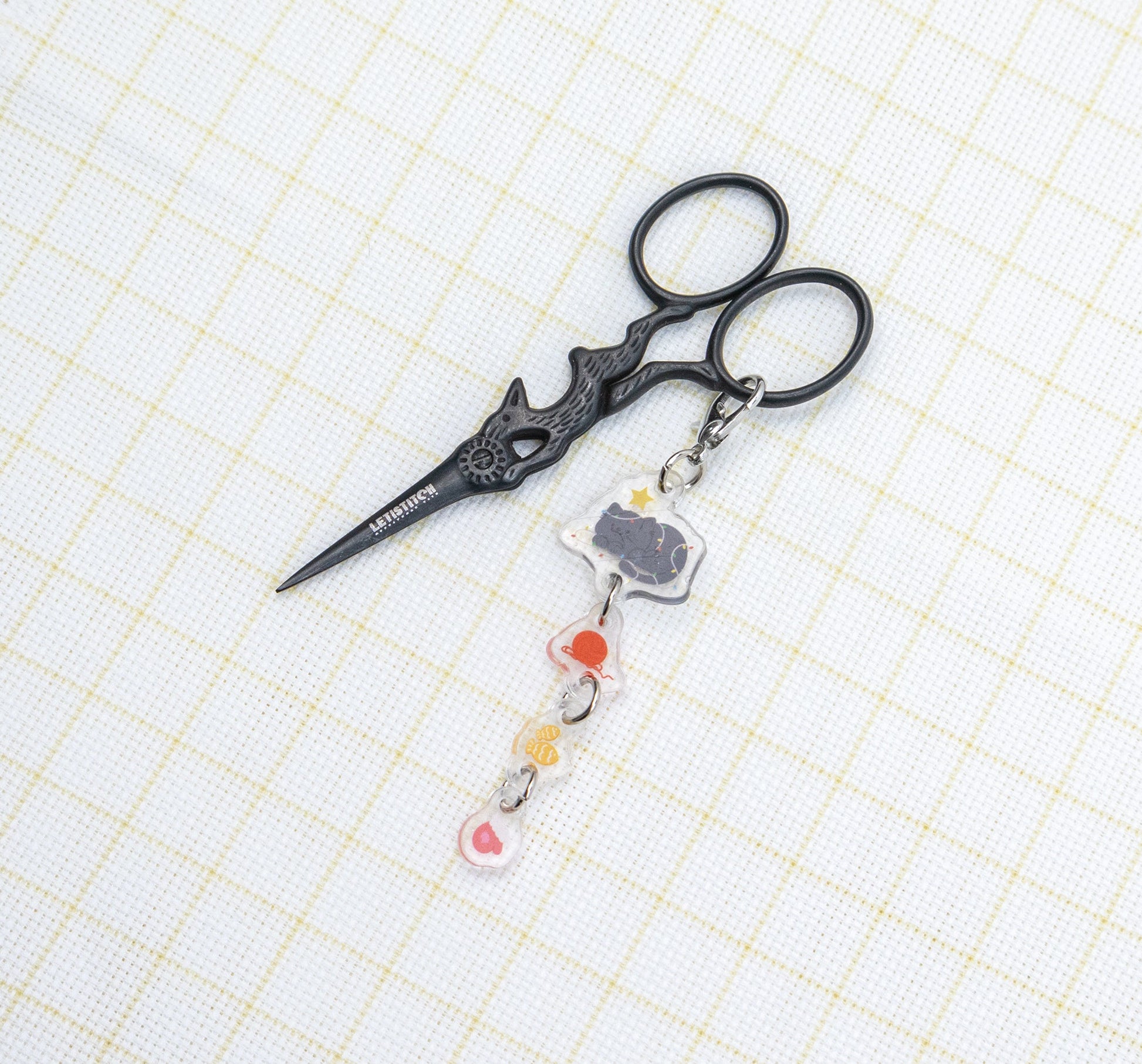 Decorative scissors with a keychain on a grid background