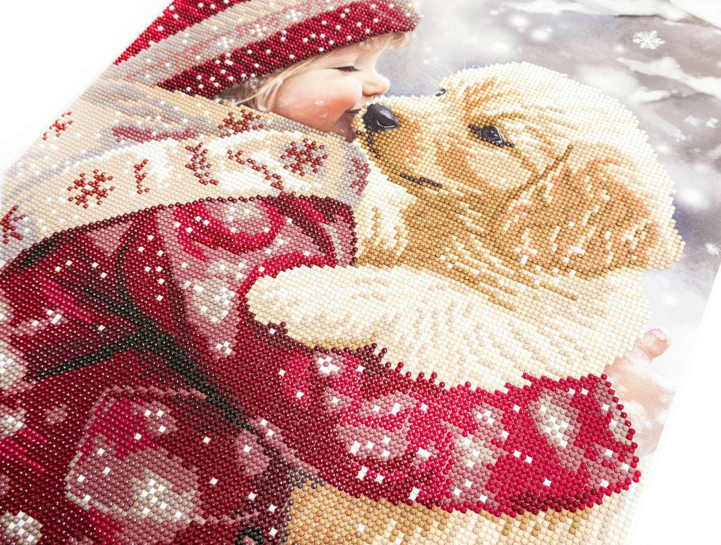 Decorative scene with a child in a red and white outfit hugging a dog, surrounded by snowflakes.