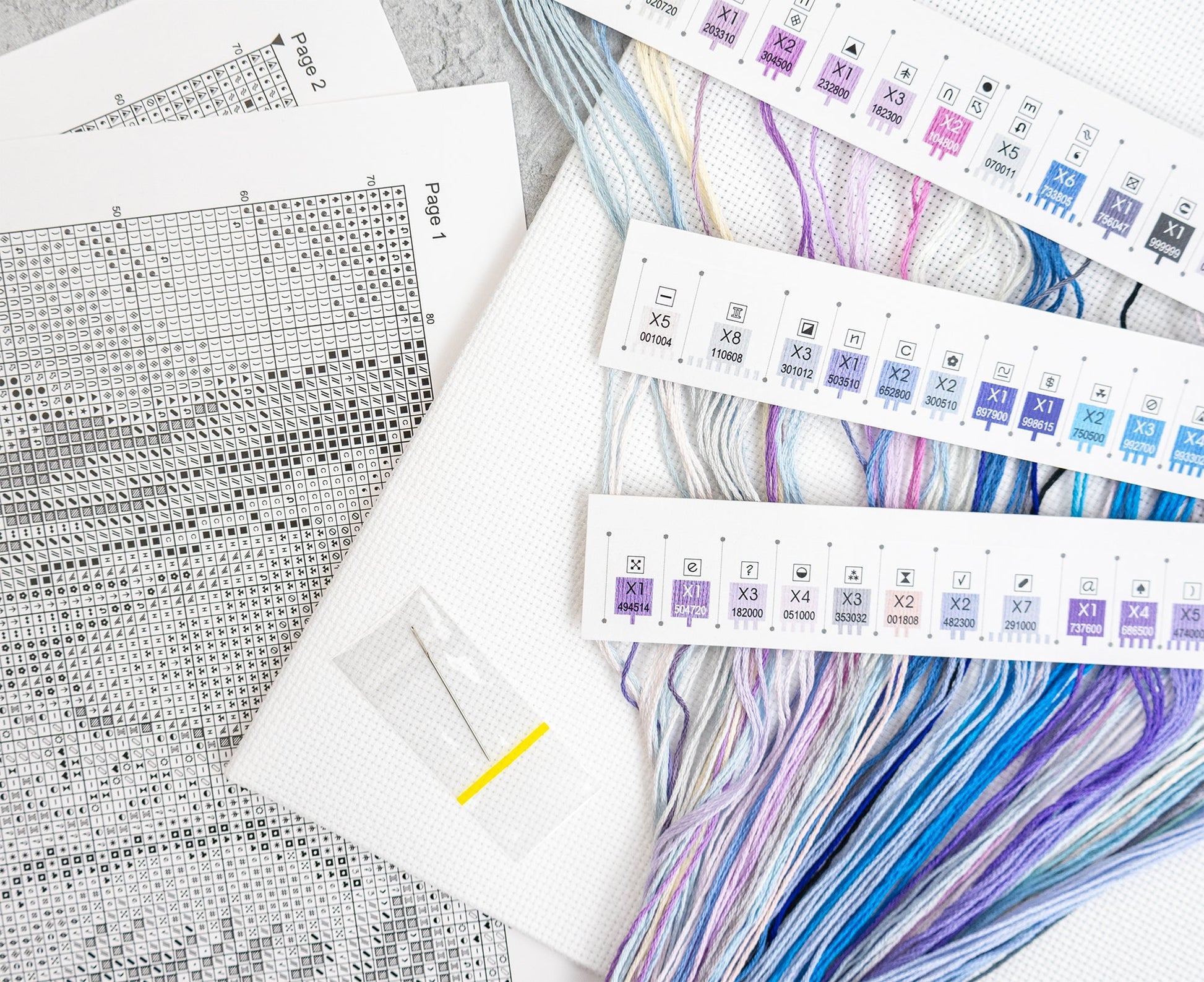 Cross stitch patterns and color swatches on a white surface