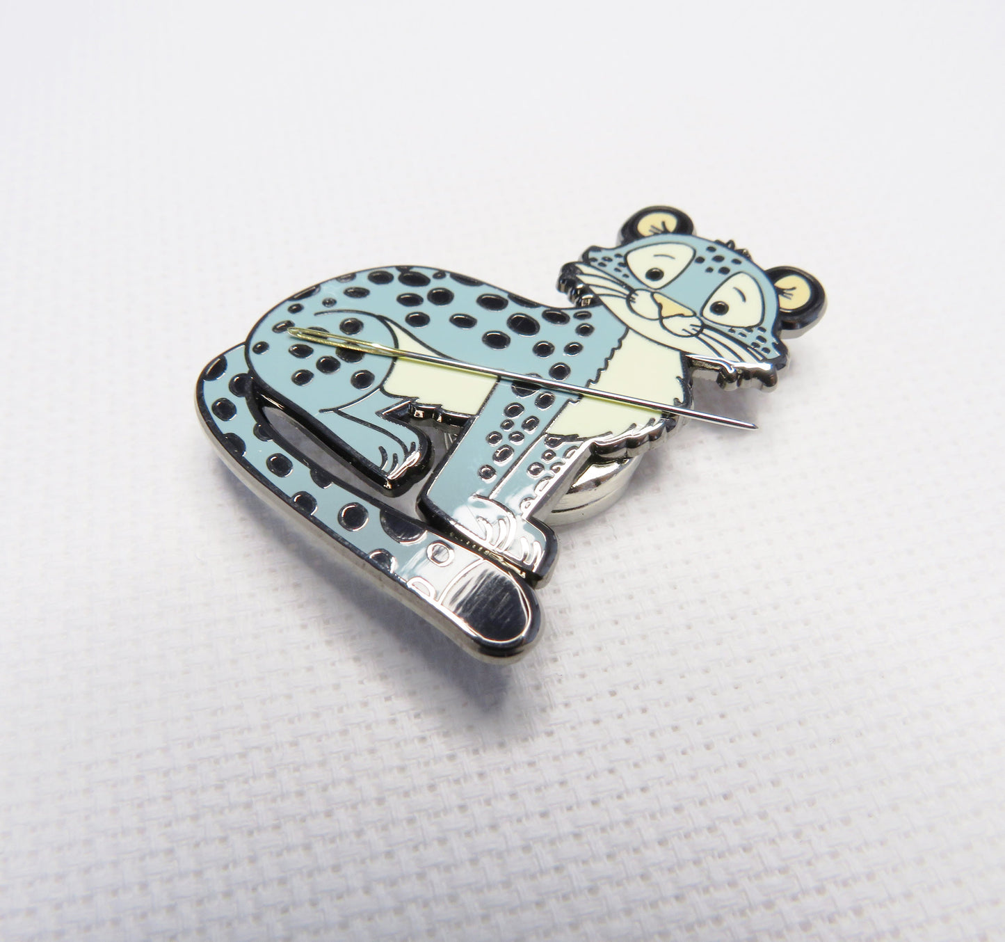 Enamel Needleminder of a cartoon character riding a scooter on a white background