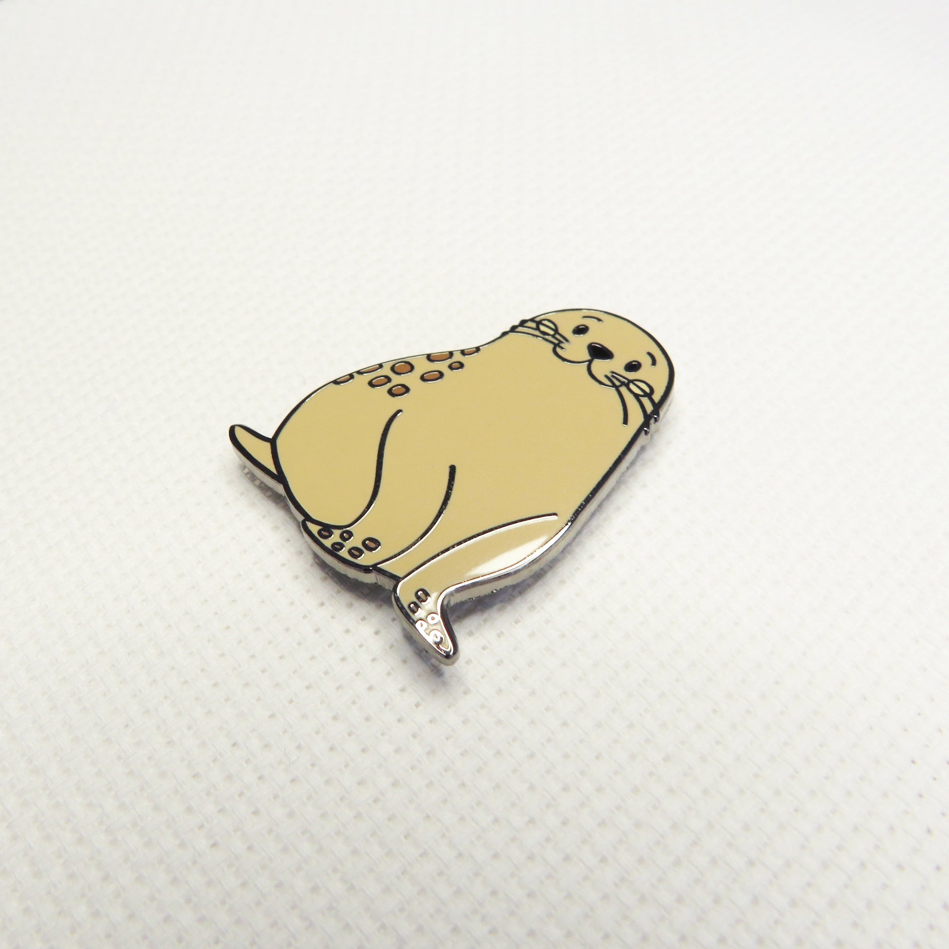 Beige seal-shaped Needleminder on a textured white background