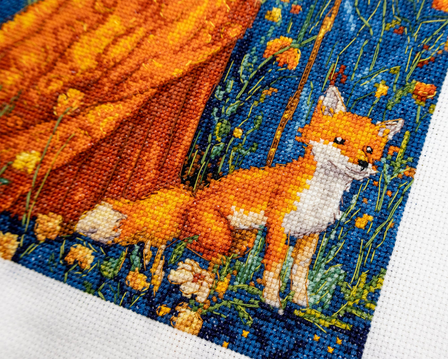 Cross-stitched fox in a field of flowers on fabric