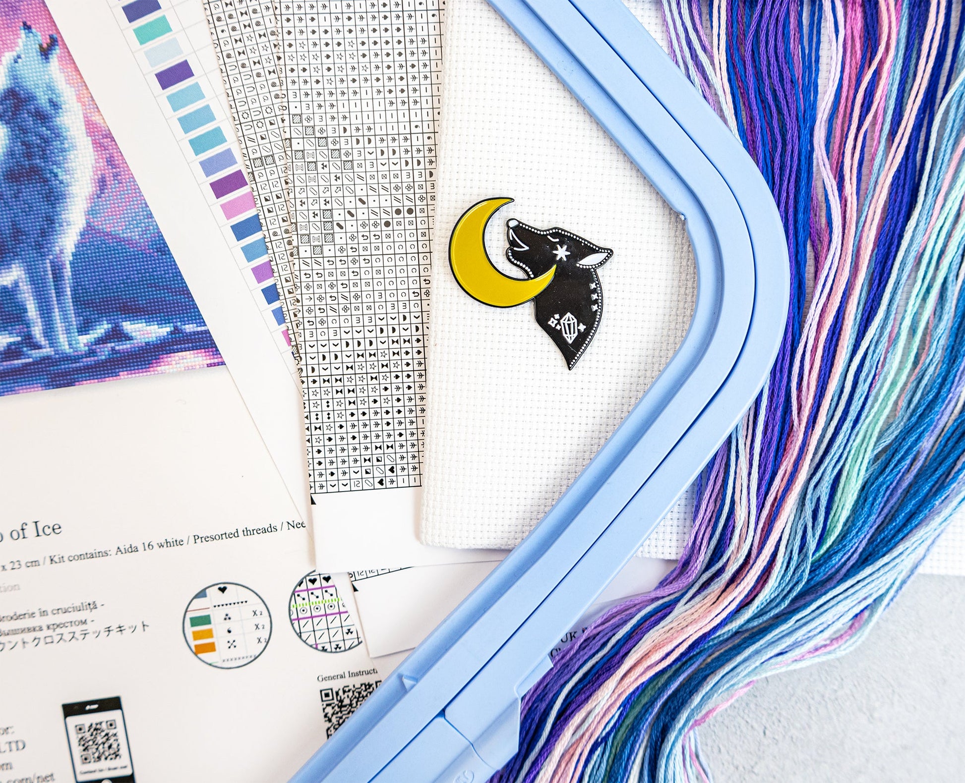 Color swatch card with a wolf and moon design, surrounded by colorful threads on a textured surface.