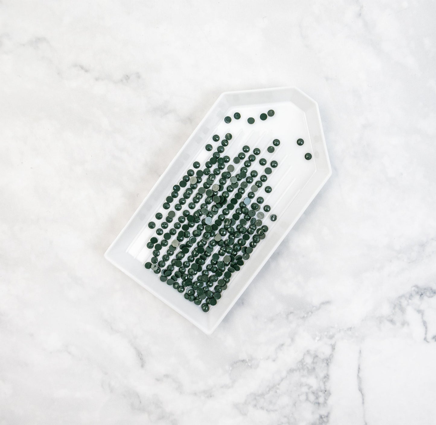 White tray with green crystals on a marble surface